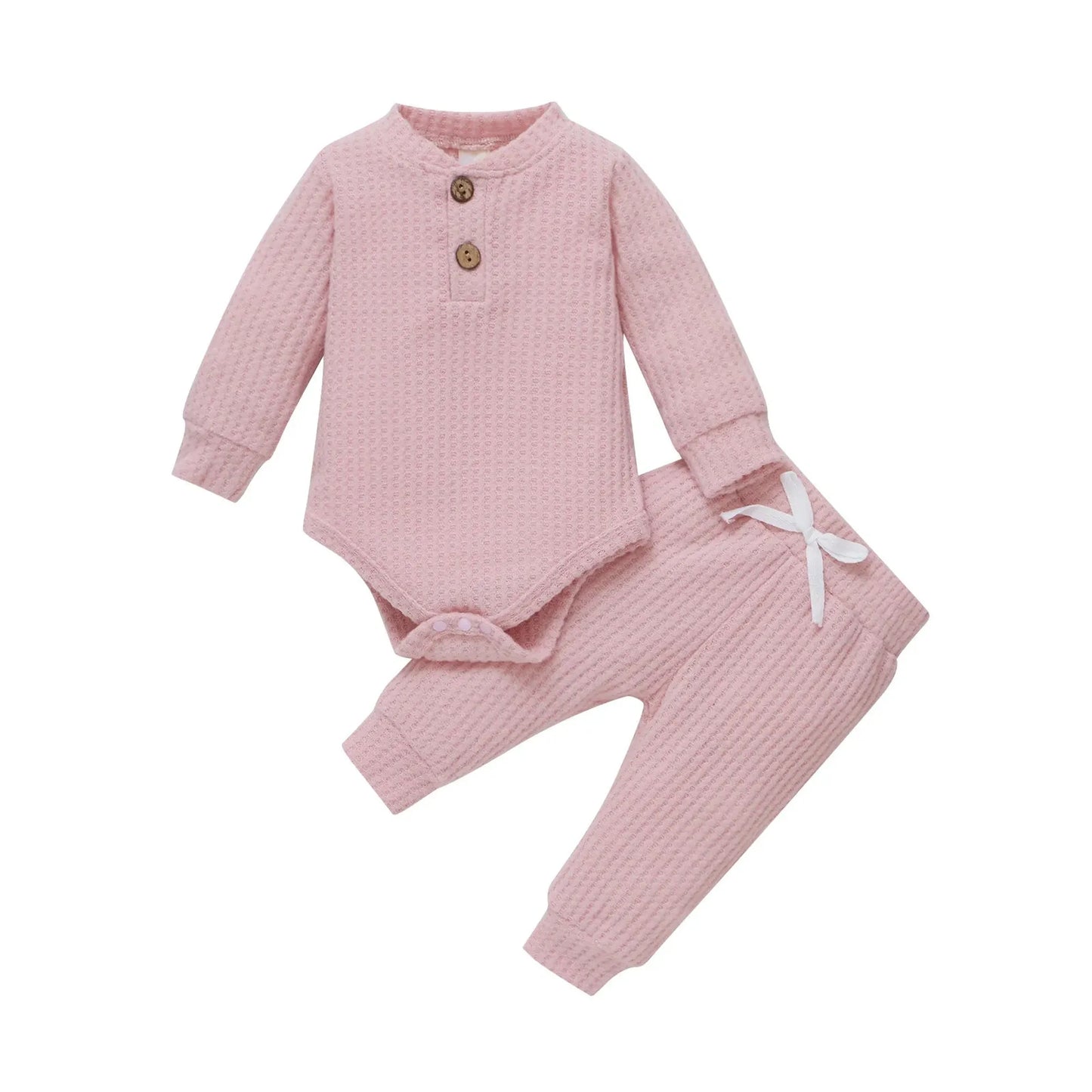Pink waffle knit long-sleeve baby bodysuit and matching pants with wooden buttons and white drawstring.