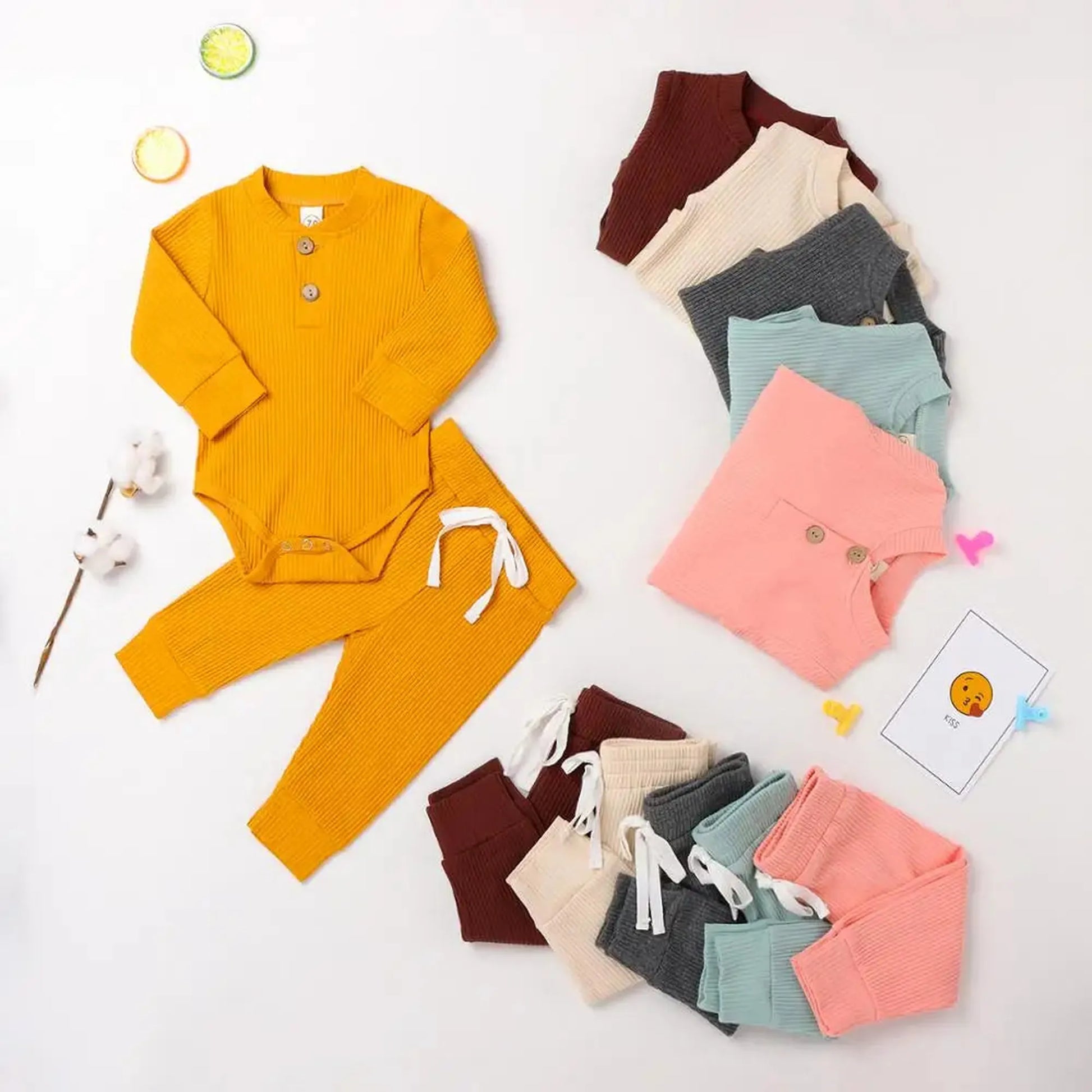 Ribbed cotton long-sleeve baby bodysuit and pants set in mustard yellow, with other color options displayed.