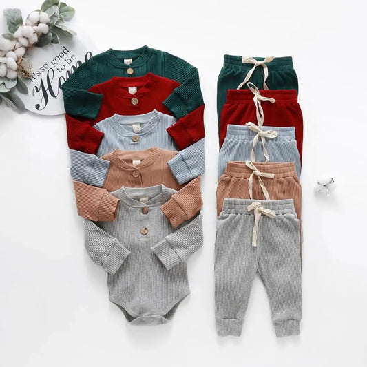 Five ribbed cotton baby outfits in green, red, blue, brown, and gray with long sleeves and matching pants.