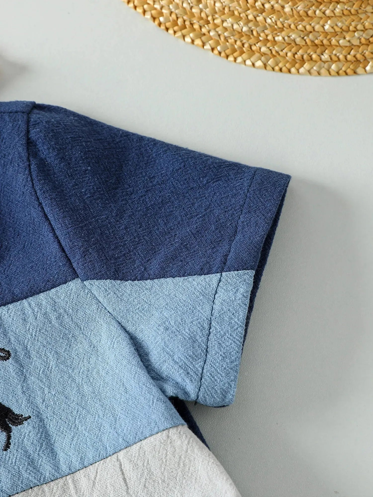 Close-up of a baby boy's short-sleeve cotton summer set, featuring blue, light blue, and white color block patchwork.