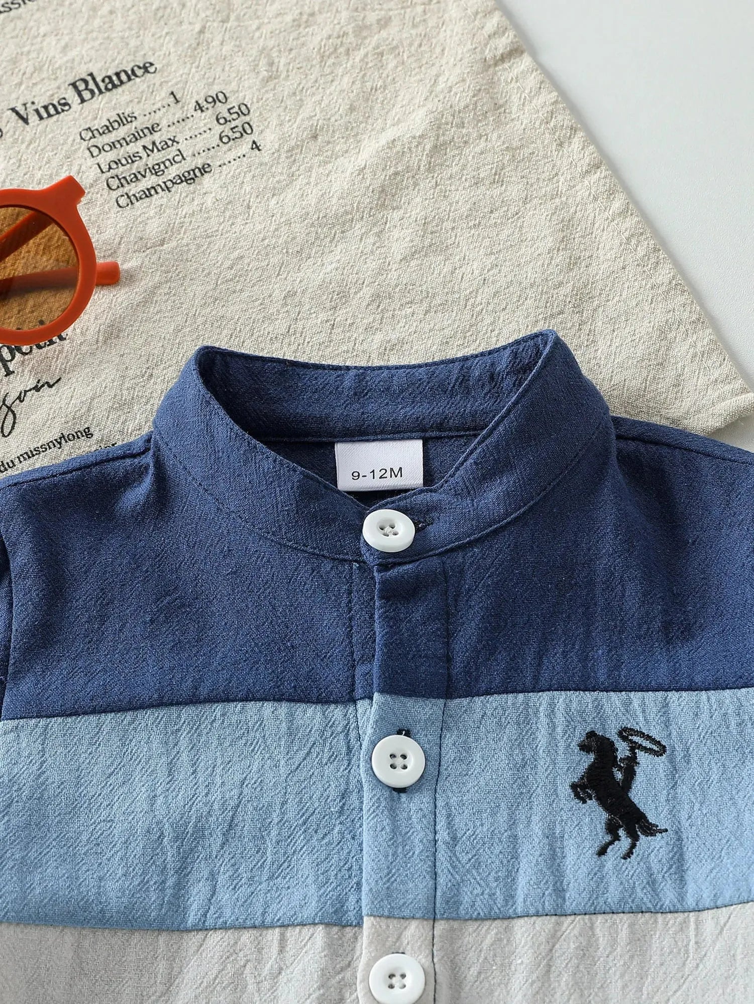Baby boy's short-sleeve cotton summer set with blue, light blue, and beige patchwork, mandarin collar, and cowboy embroidery.