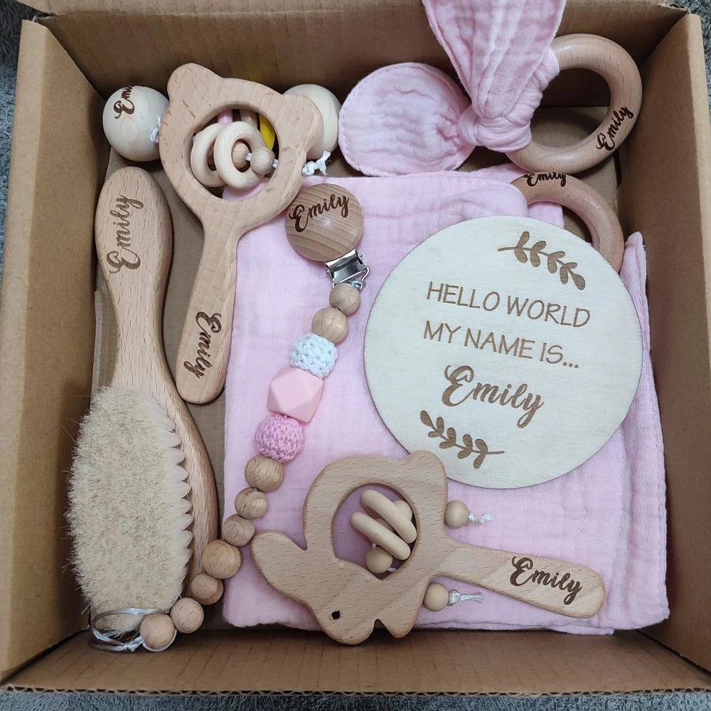 Personalized 8-piece natural wood baby gift set with pink accents, including rattles, brush, and pacifier clip.