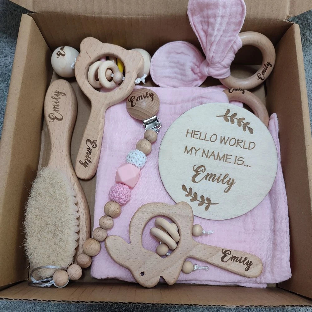 Personalized 8-piece natural wood baby gift set with pink blanket, brush, teethers, pacifier clip, and name plaque.