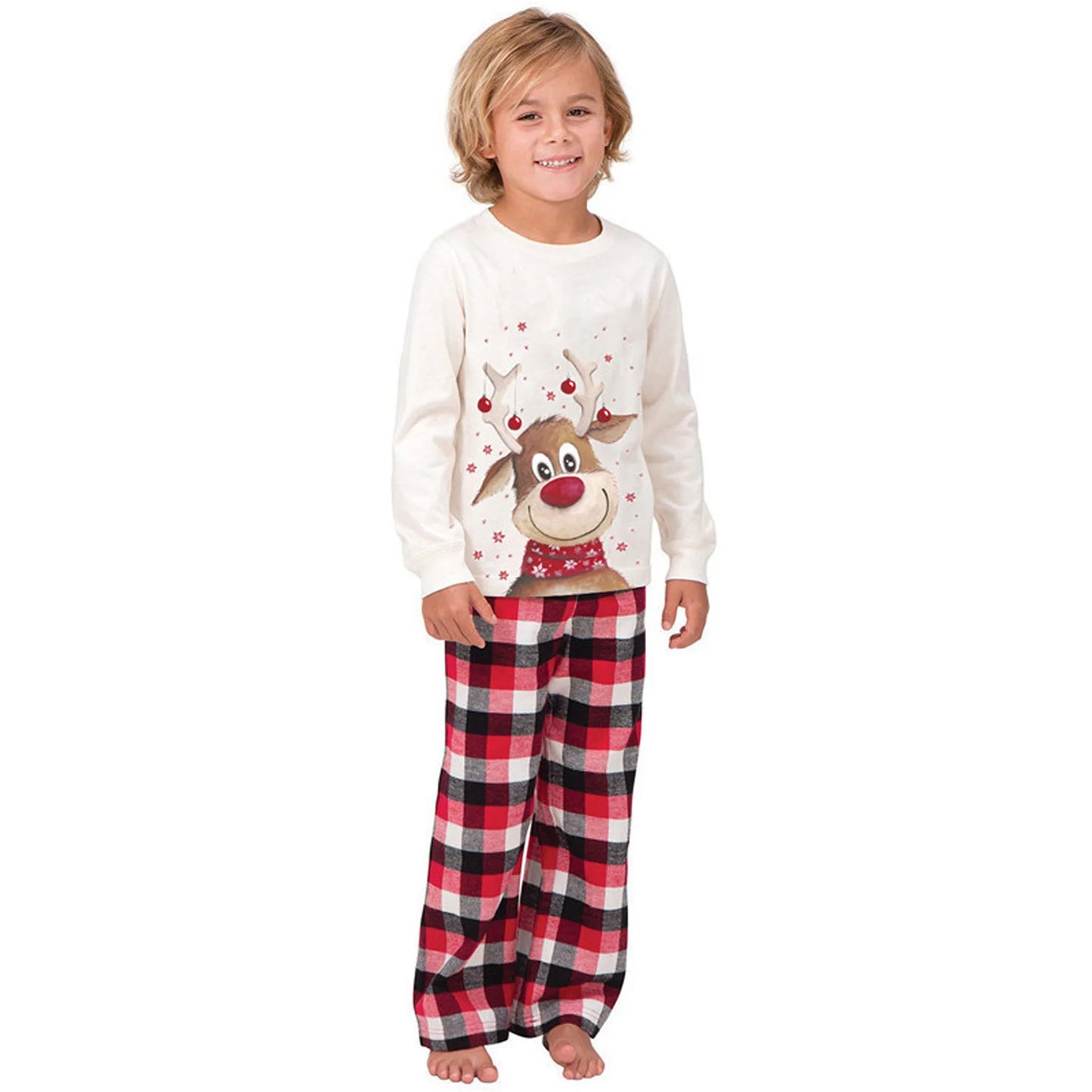 Child in matching Christmas pajamas: cream long-sleeve top with reindeer, red and black plaid pants.