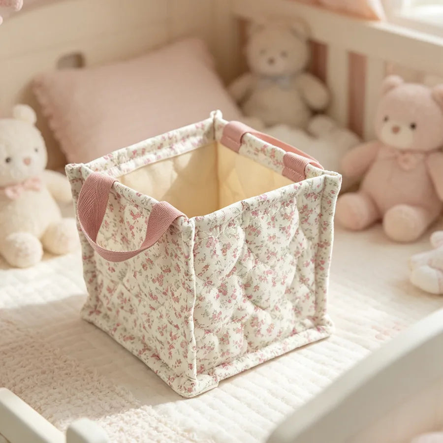 Square quilted storage basket with pink floral pattern and handles, ideal for nursery organization.