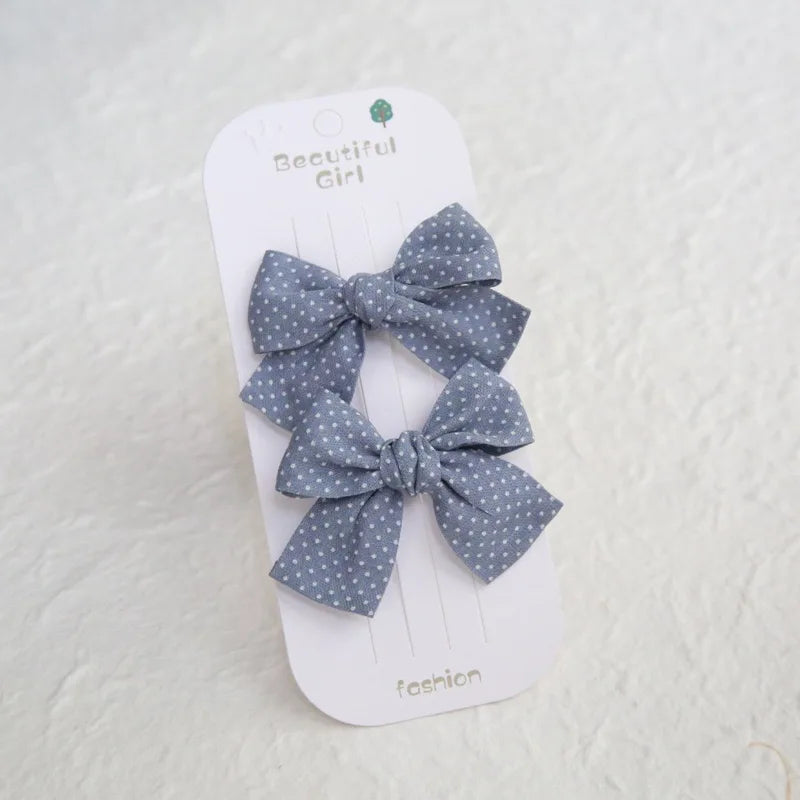Two blue cotton hair bows with white polka dots on a "Beautiful Girl" card.