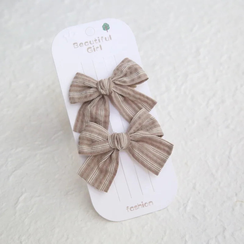 Two beige striped cotton bow hair clips for girls on a white "Beautiful Girl" card.