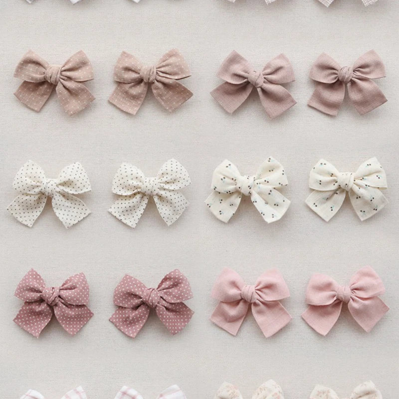 Assortment of elegant cotton hair bows for girls in pink, beige, and white, some with polka dots.