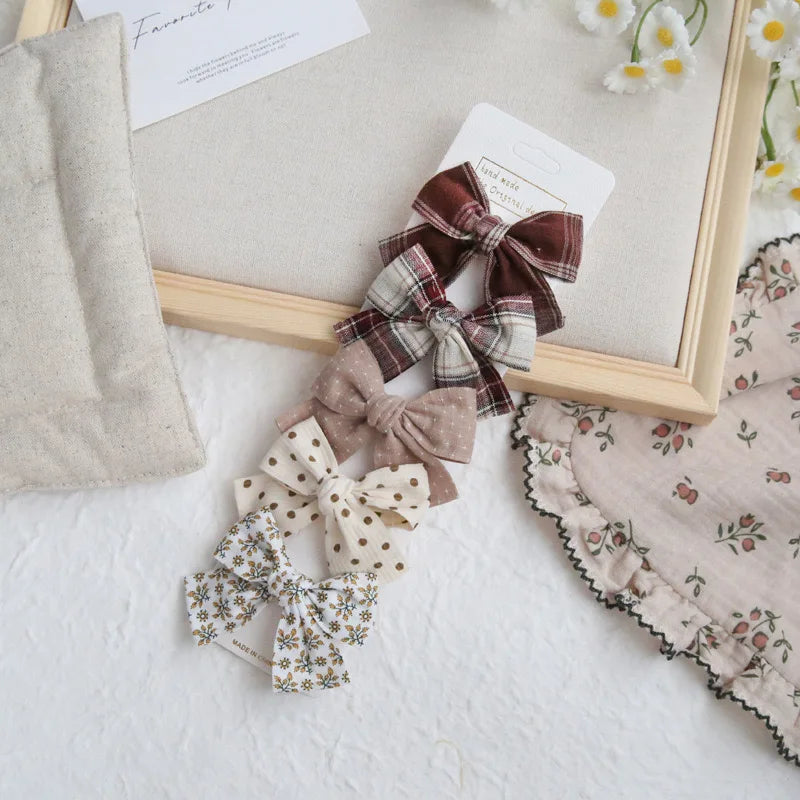 Set of five girls' hair clips with elegant fabric bows in plaid, polka dot, and floral patterns.