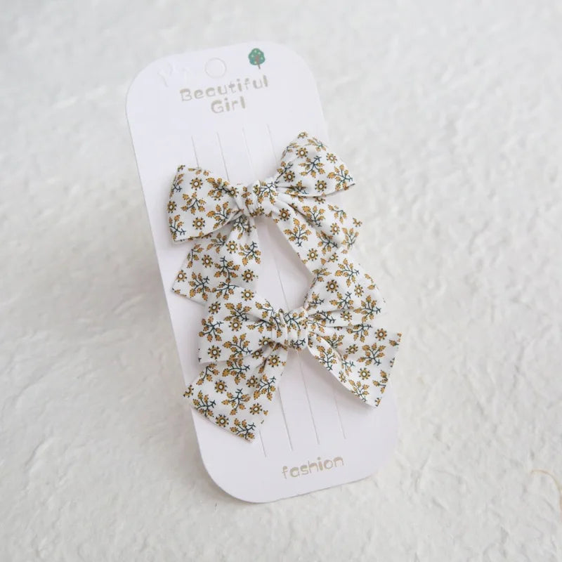 Two white cotton hair clips with yellow floral bows for girls.