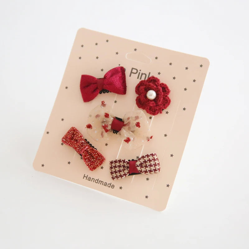 Set of five red and cream baby hair clips with bows, glitter, and a flower design.