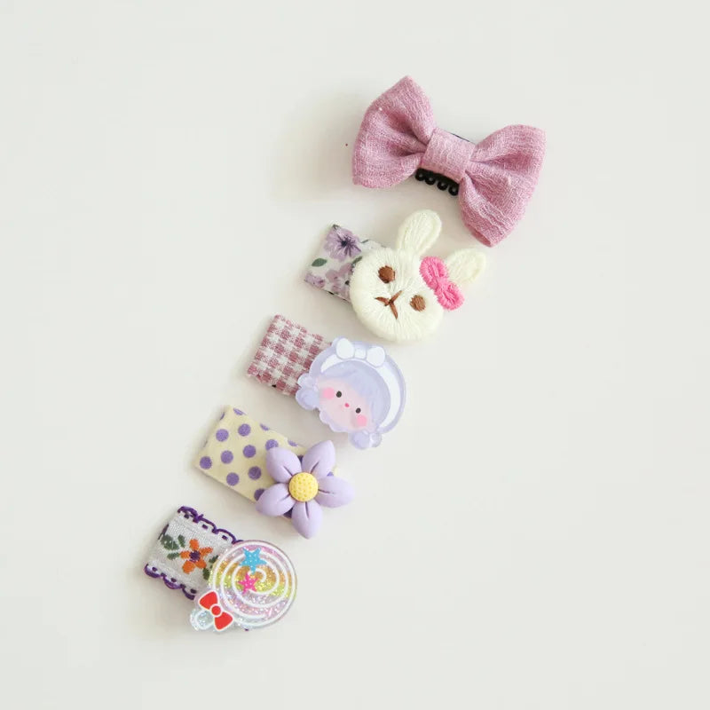 Set of five colorful baby hair clips with decorative bows, a bunny, a girl, a flower, and a lollipop design.