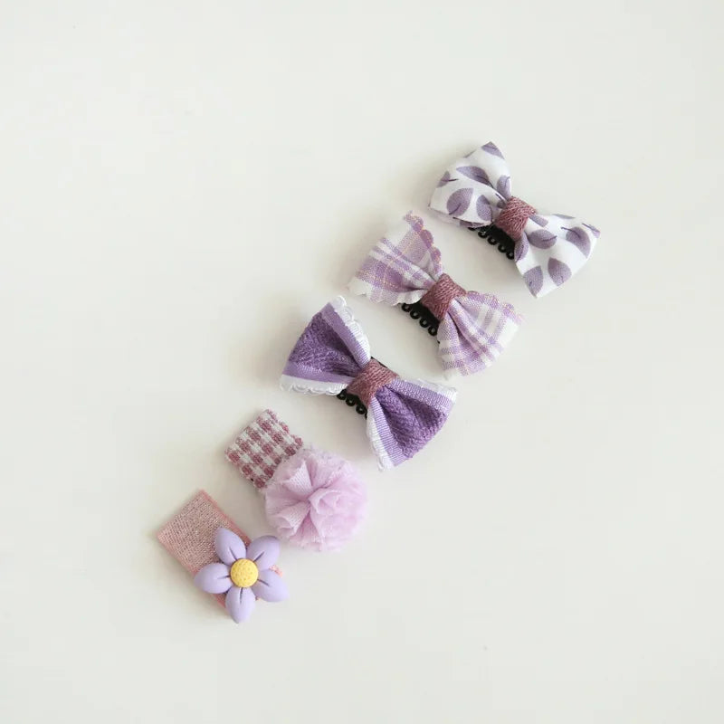 Set of four purple and pink baby hair clips with decorative bows and a flower.