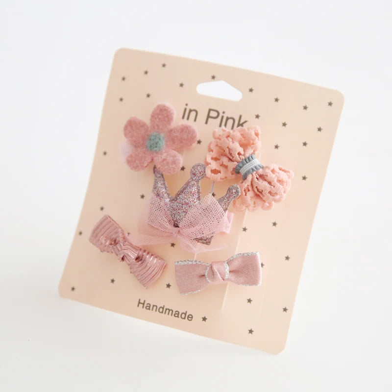 Pink baby hair clips set with flower, crown, and bow designs on a "in Pink" card.
