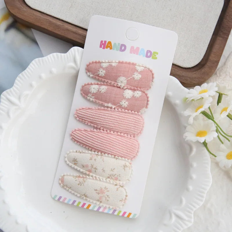 Set of 6 handmade pink and white cotton hair clips for babies and girls, with floral and ribbed designs.