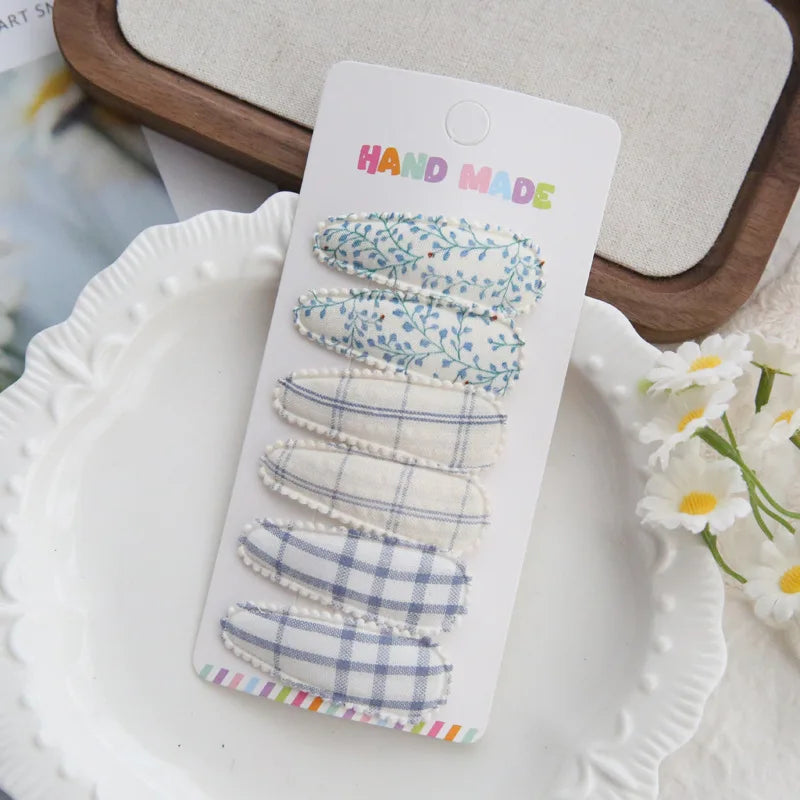 Handmade set of 6 fabric hair clips for babies and girls, featuring blue floral and plaid patterns.