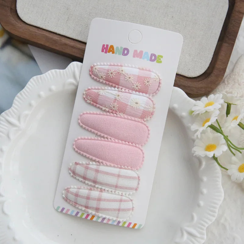Handmade set of 6 pink and white plaid and floral fabric snap hair clips for babies and girls.