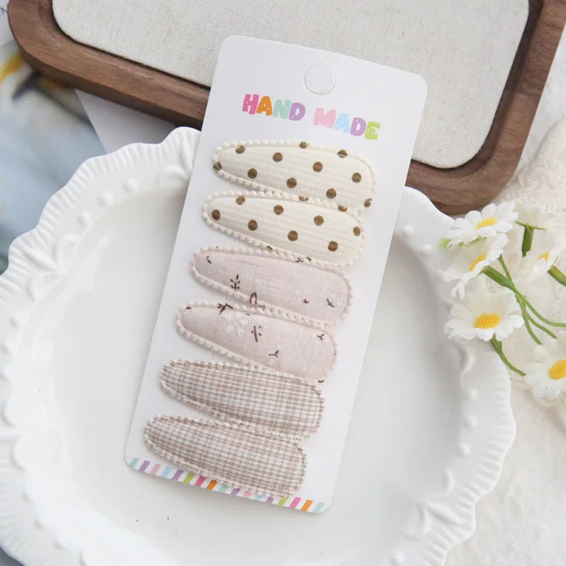 Handmade set of 6 fabric hair clips for babies and girls, featuring polka dots, floral, and plaid patterns.