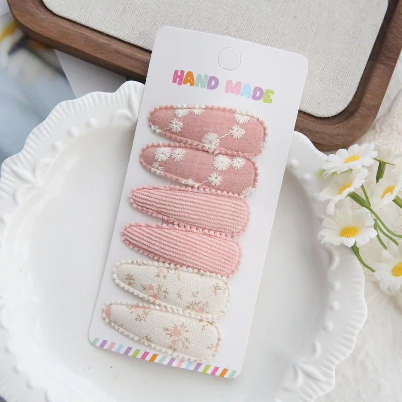 Set of 6 handmade pink and cream cotton hair clips for babies and girls, featuring floral and ribbed designs.