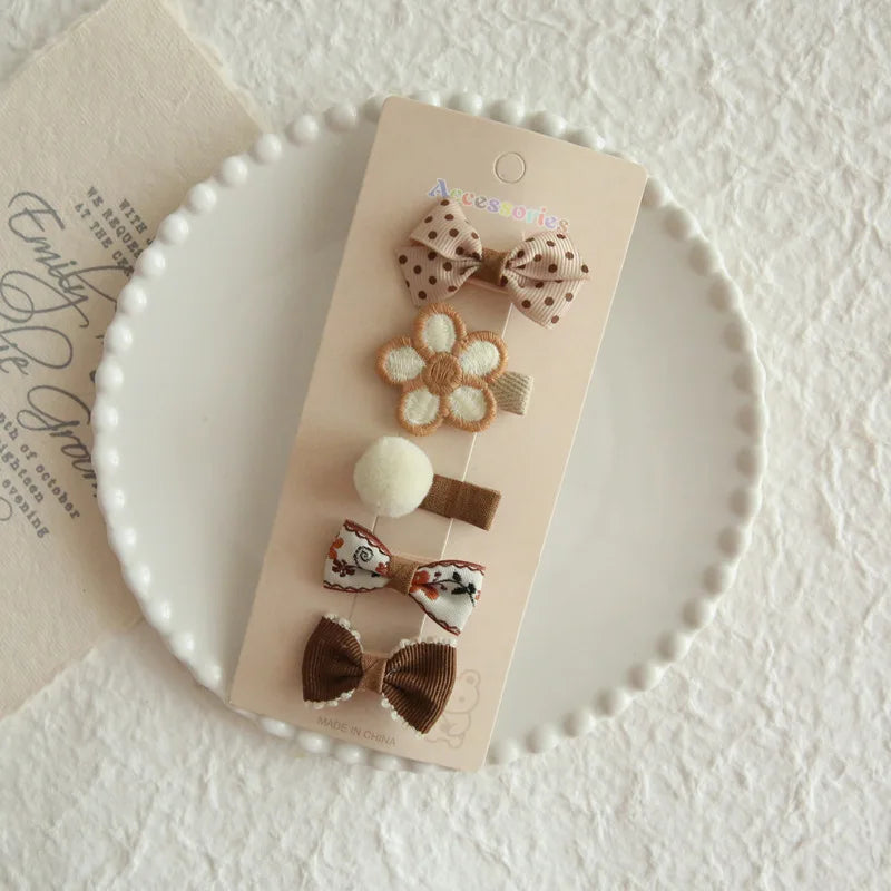 Set of 5 brown and beige floral hair clips for babies and girls, featuring bows, a flower, and a pom-pom.