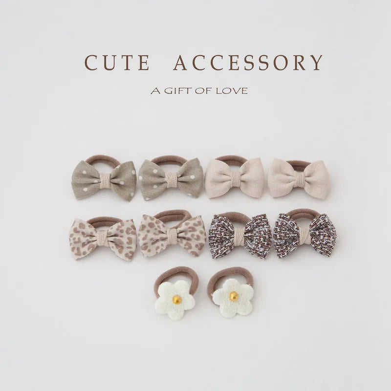 10-pack of girls' hair ties and clips: beige bows (polka dot, leopard, tweed) and white flower ties.