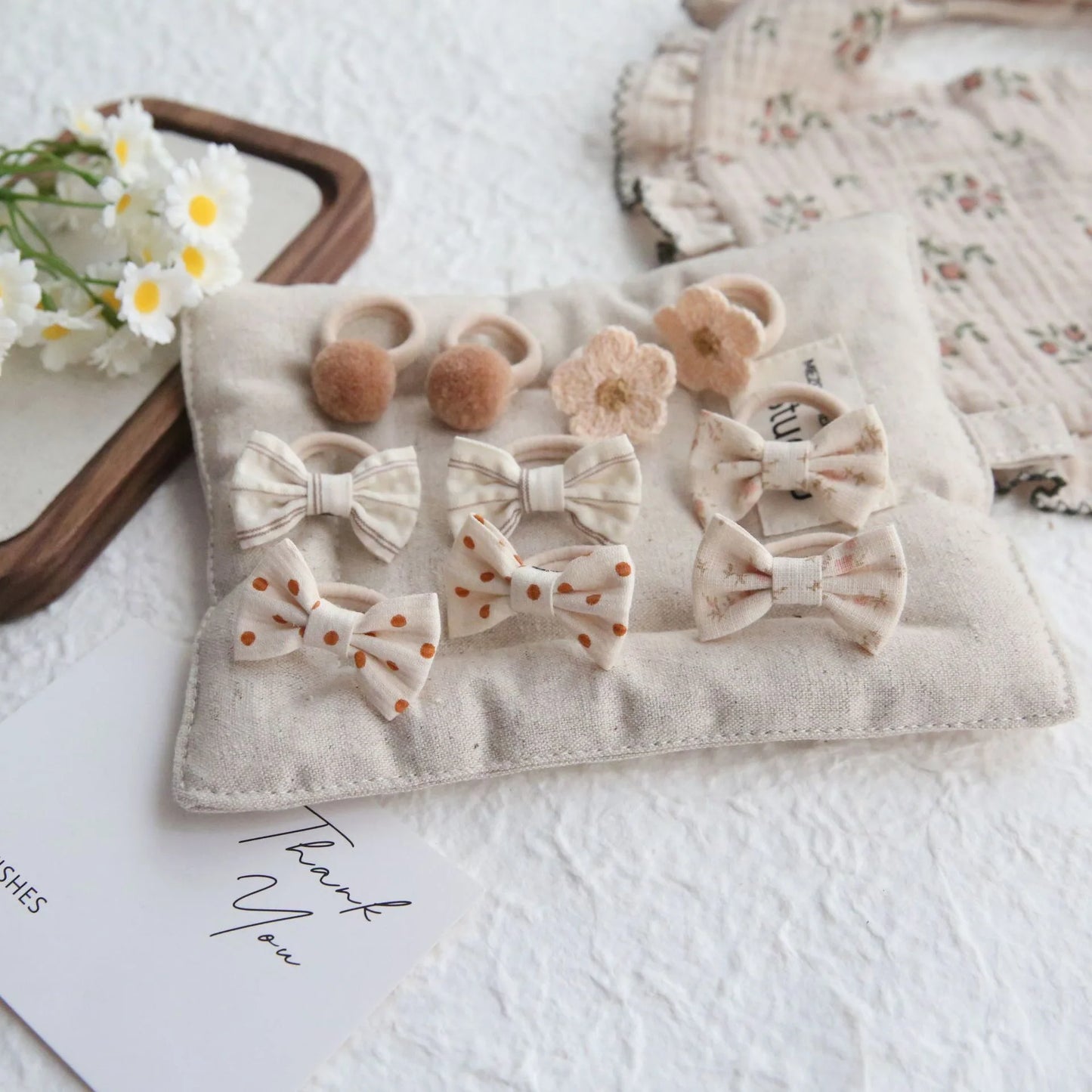 10-piece set of girls' cotton hair ties and clips in neutral tones, featuring bows, pom-poms, and floral designs.