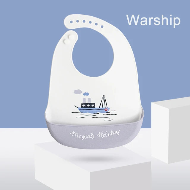 White silicone baby bib with a blue boat design and "Magical Holiday" text, featuring an adjustable neck and food-catching pocket.