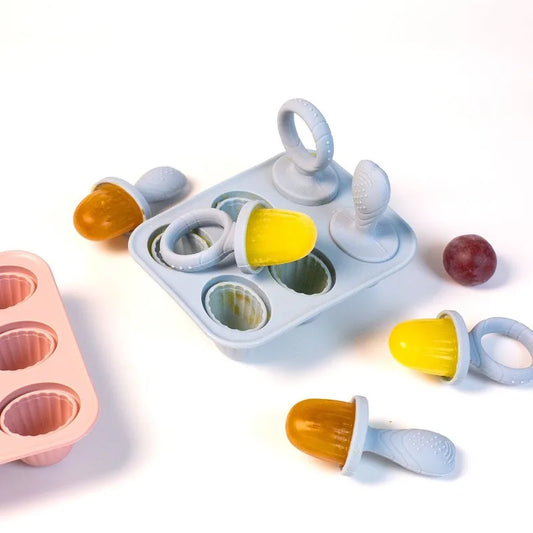 Light blue silicone baby popsicle mold with yellow and orange fruit pops, plus a pink mold.