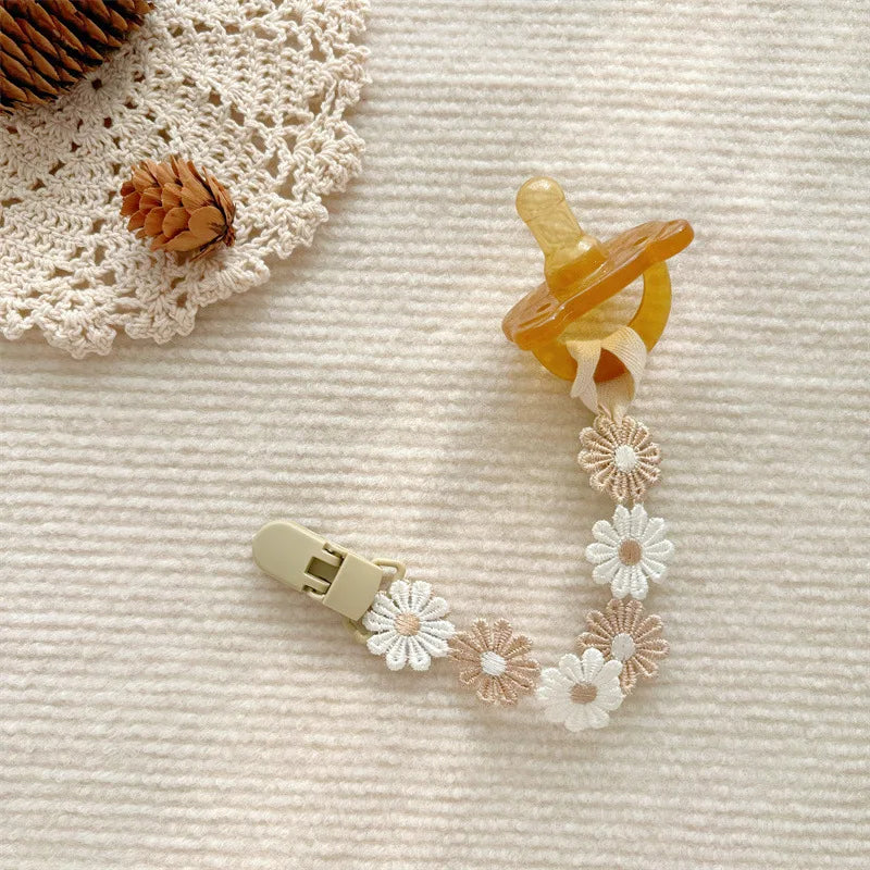 Beige and white daisy flower pacifier clip with a natural rubber pacifier.