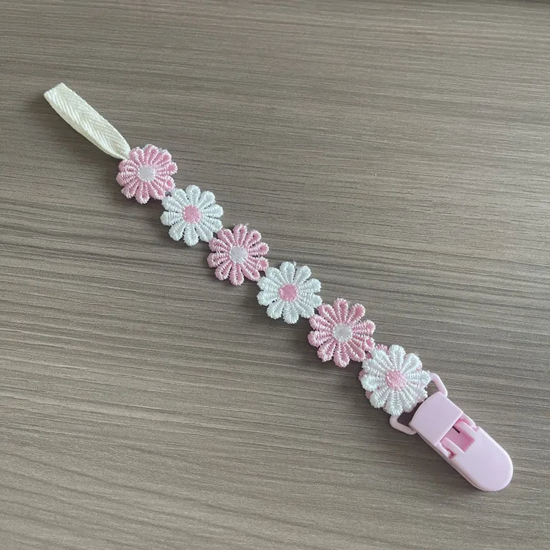 Pink and white daisy flower pacifier clip made of soft polyester, with a light pink plastic clasp.
