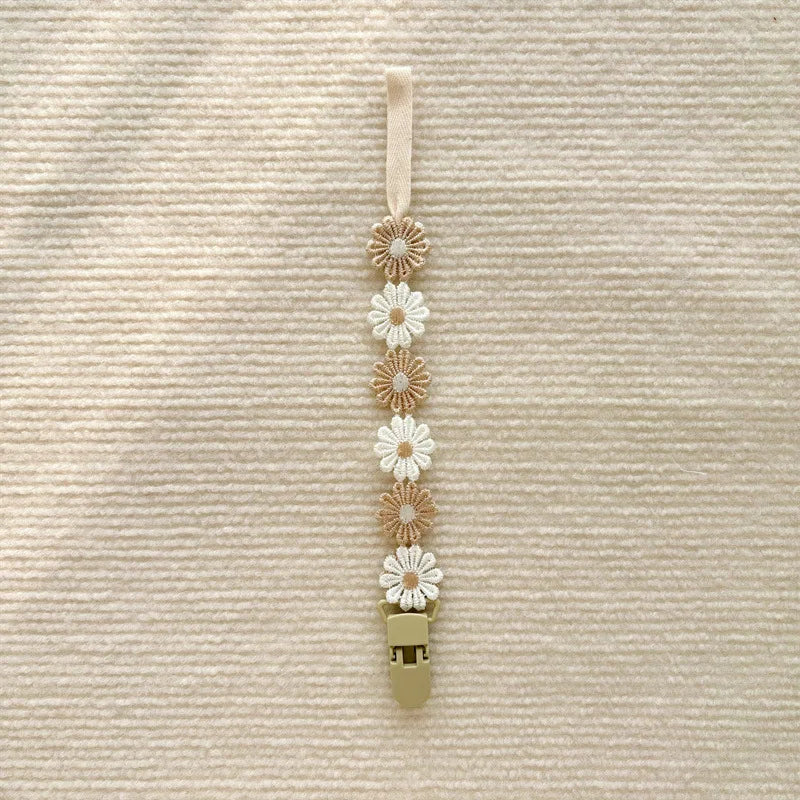 Beige and white daisy flower pacifier clip, polyester, 25cm long, with a secure plastic clasp.