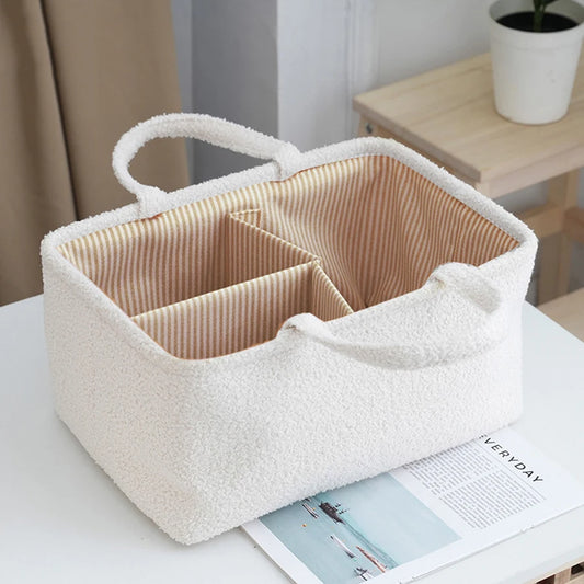 Creamy white sherpa diaper caddy with striped interior dividers and two soft handles.