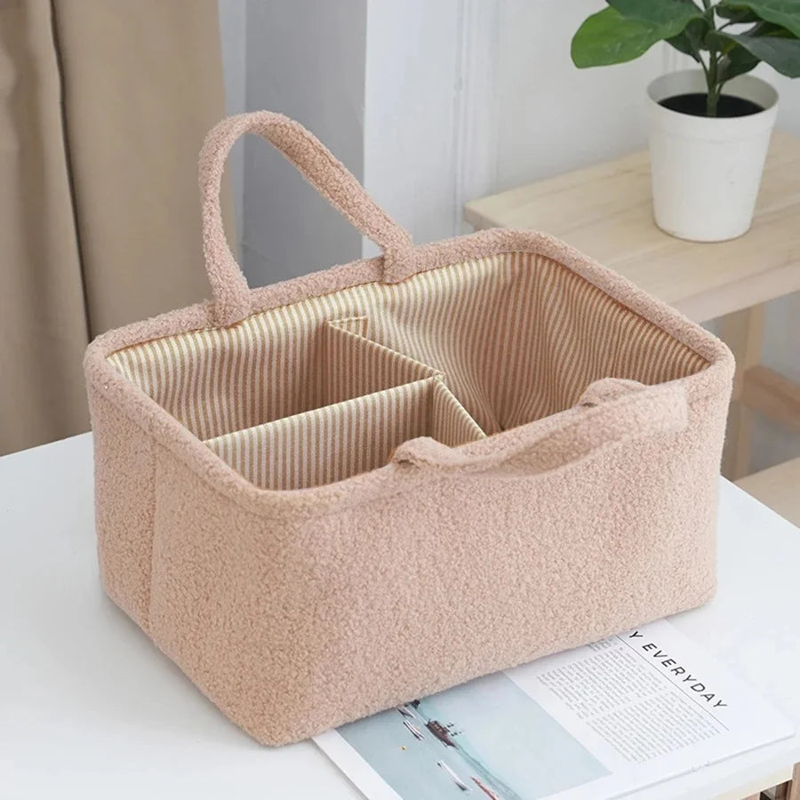 Pink polyester baby organizer caddy with striped lining and multiple compartments, on a white table.