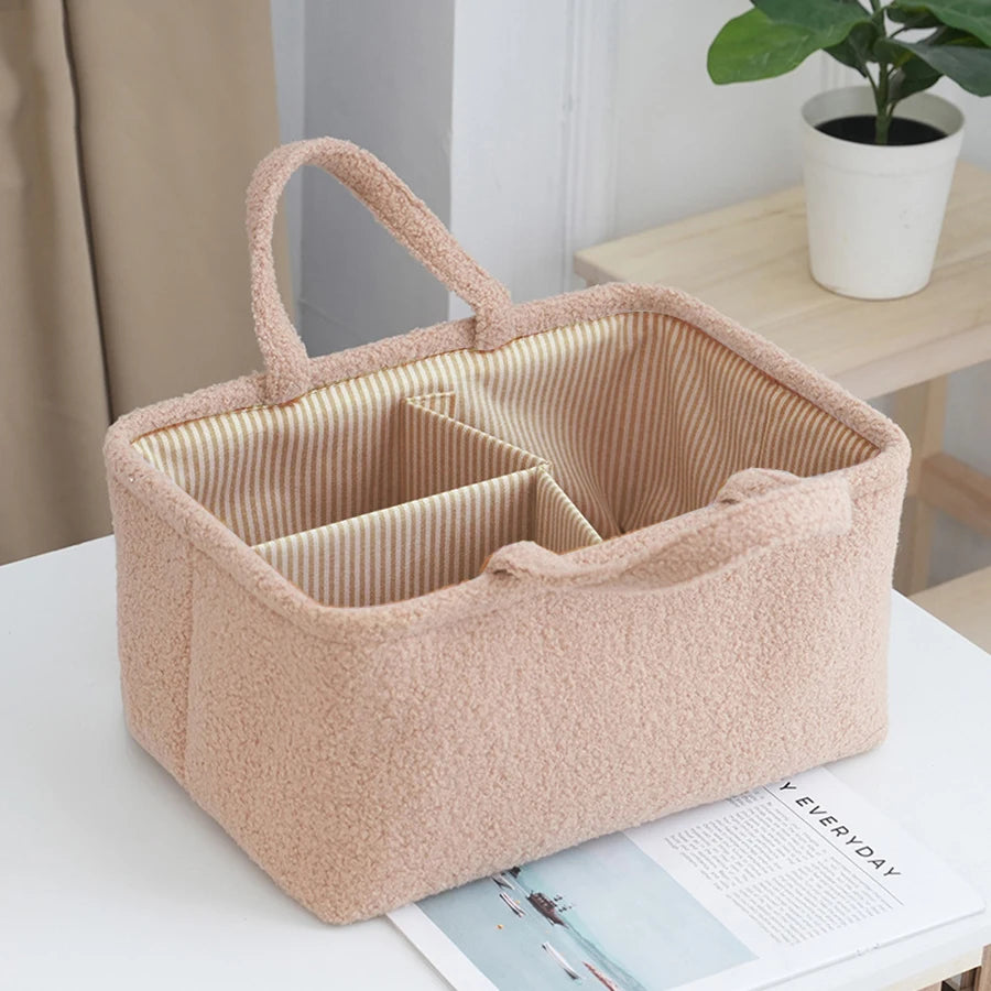 Pink fuzzy polyester diaper caddy with striped interior dividers and two handles.