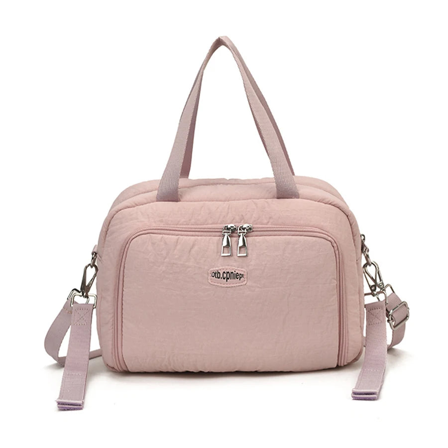 Pink polyester diaper bag with dual zippers, front pocket, top handles, and detachable shoulder strap.