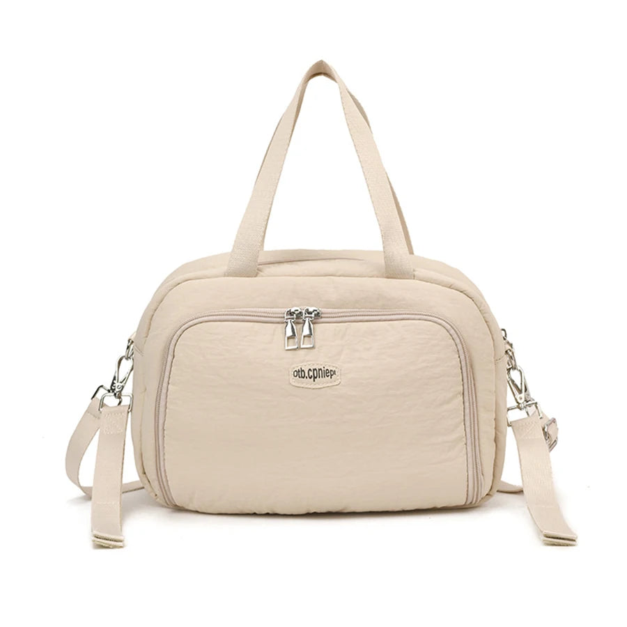 Beige polyester diaper bag with top handles, front zip pocket, and detachable shoulder strap.