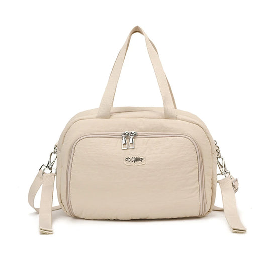 Beige polyester diaper bag with top handles, front zip pocket, and detachable shoulder strap.