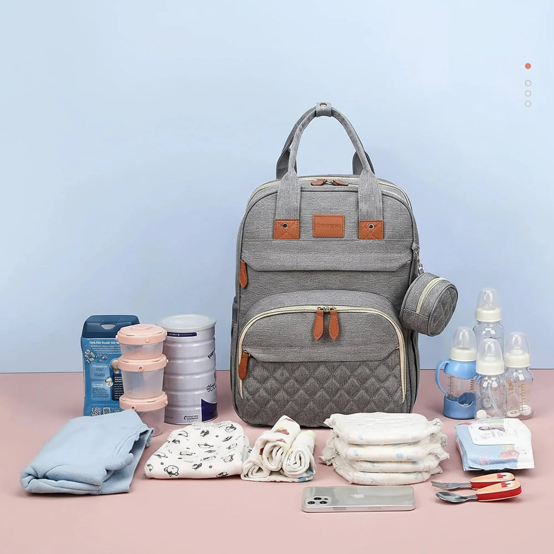 Gray 3-in-1 diaper bag backpack with quilted front pocket, brown accents, and baby essentials.
