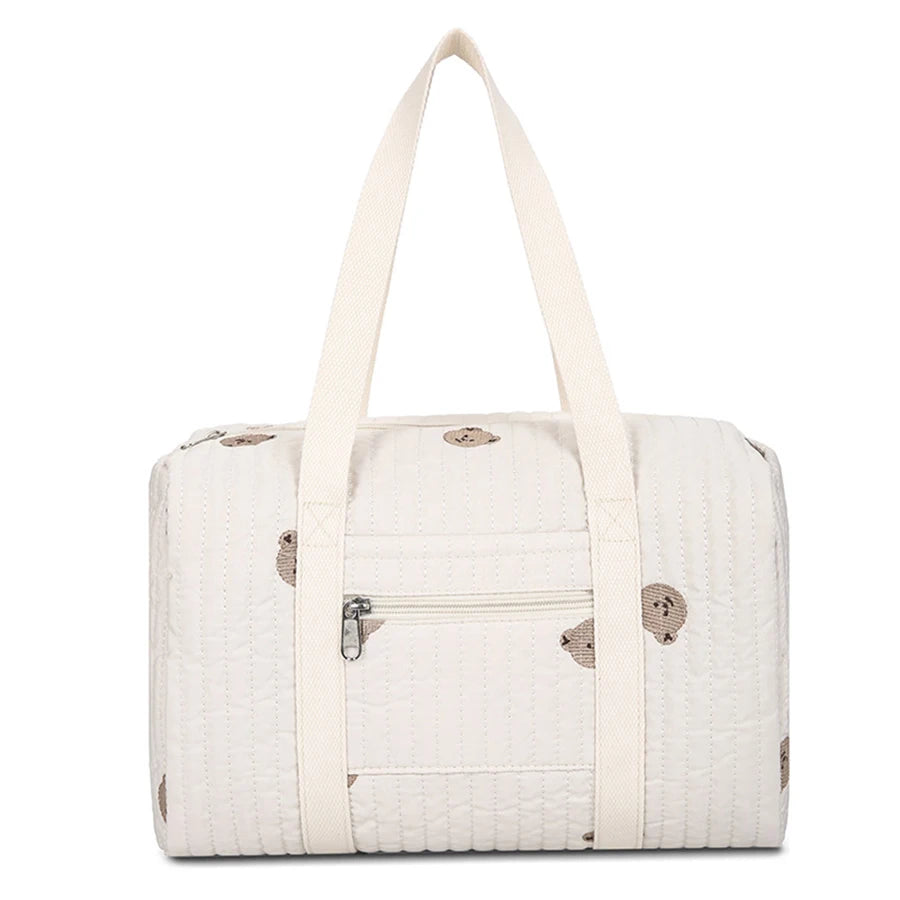 Quilted cream diaper bag with brown bear print, front zipper pocket, and sturdy top handles.