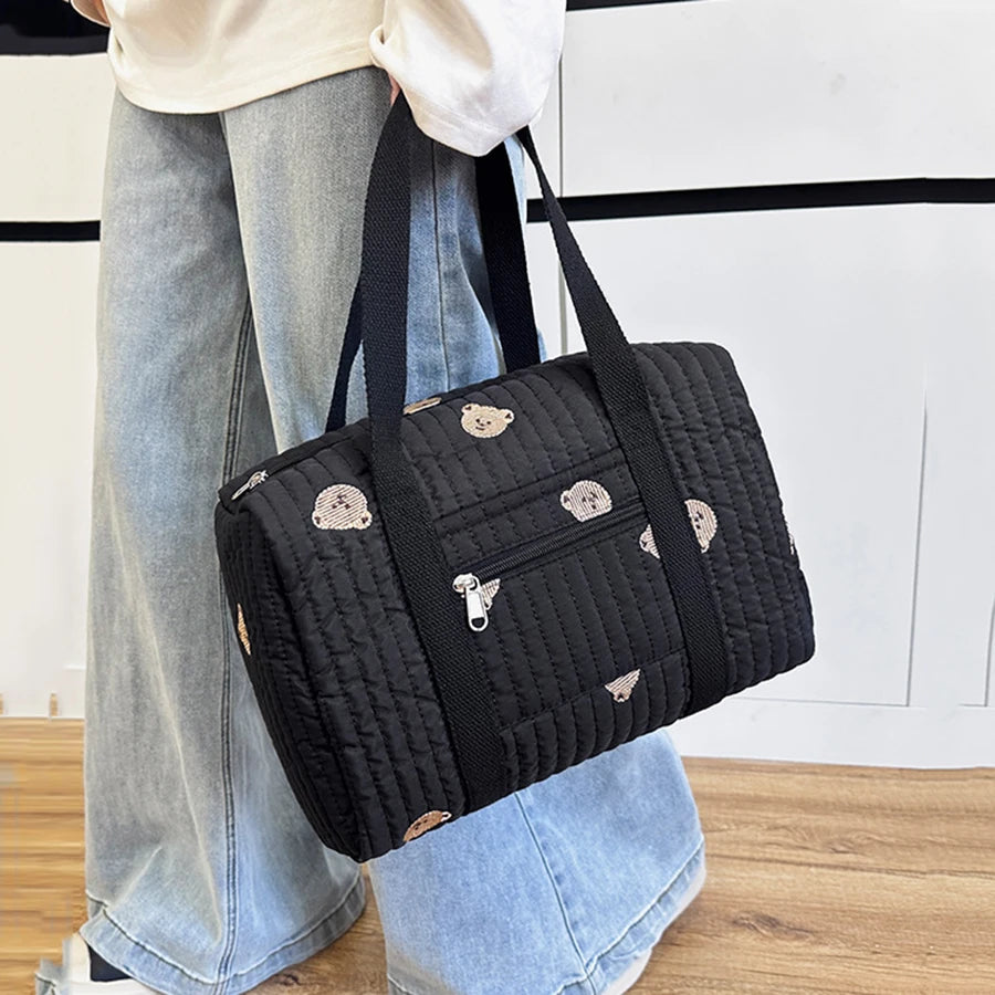 Black quilted diaper bag with cute bear embroidery, front zipper pocket, and sturdy black handles.