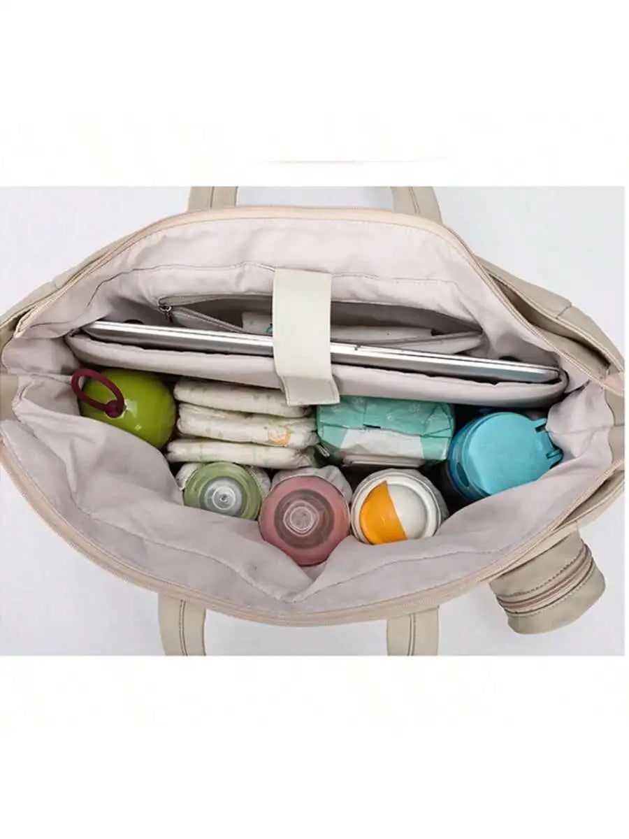 Open beige diaper tote bag with multiple compartments, holding a tablet, diapers, baby bottles, and containers.