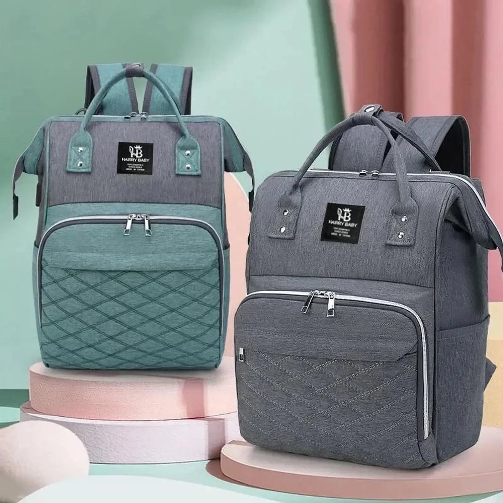 Two large Oxford fabric diaper backpacks, one gray and teal, the other dark gray, with quilted pockets.