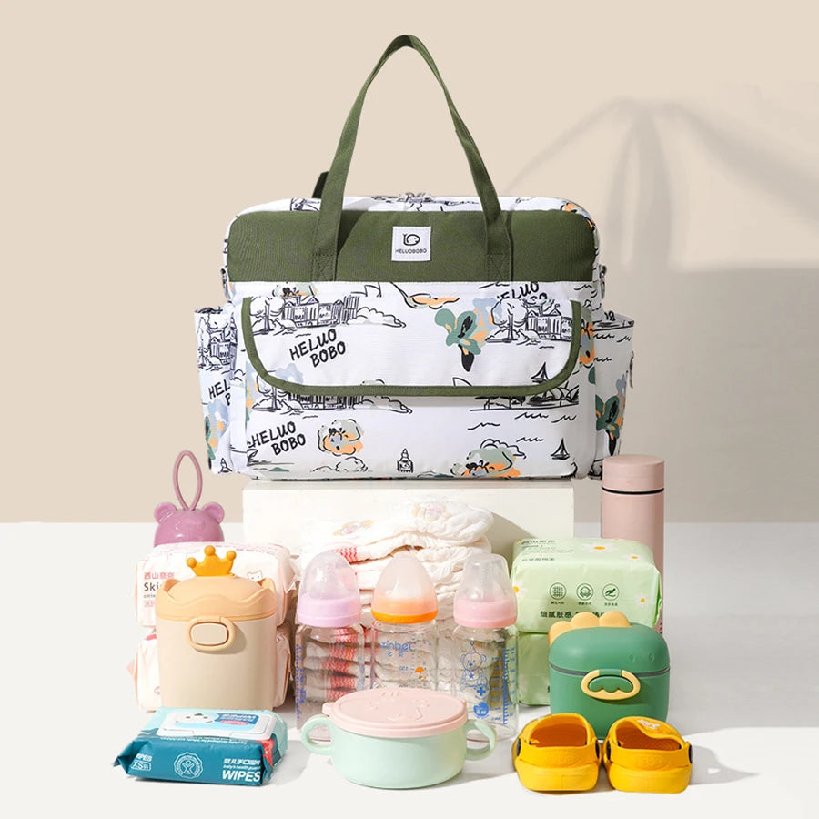 White and green Oxford fabric diaper bag with cartoon print, surrounded by baby essentials.