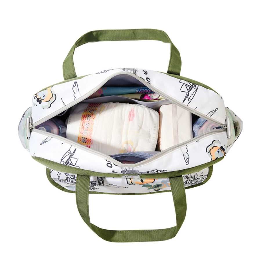 Open white Oxford fabric diaper bag with green trim, filled with diapers and baby bottles.