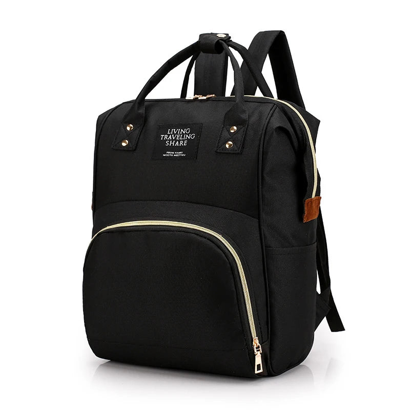 Black canvas diaper backpack with gold zippers, top handles, and shoulder straps.