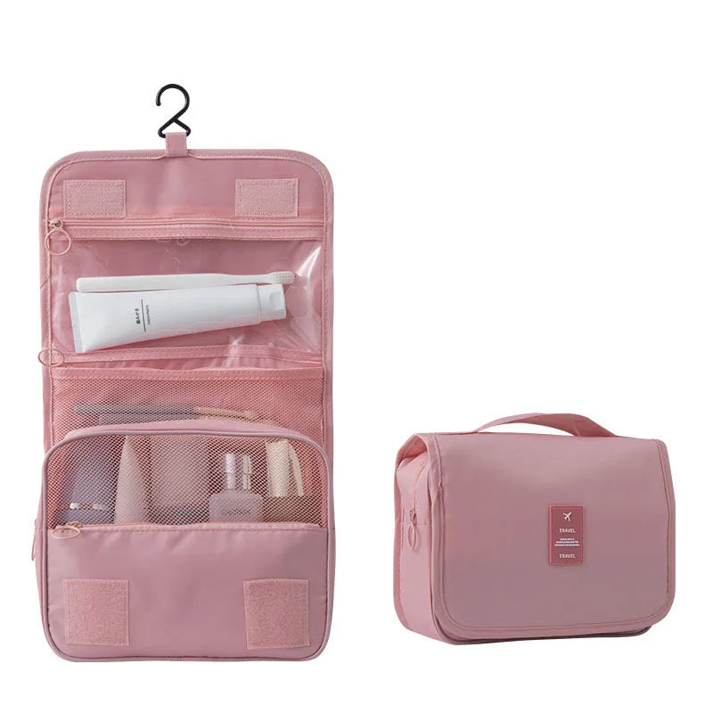 Pink polyester hanging travel toiletry bag, open with compartments and closed with a handle.