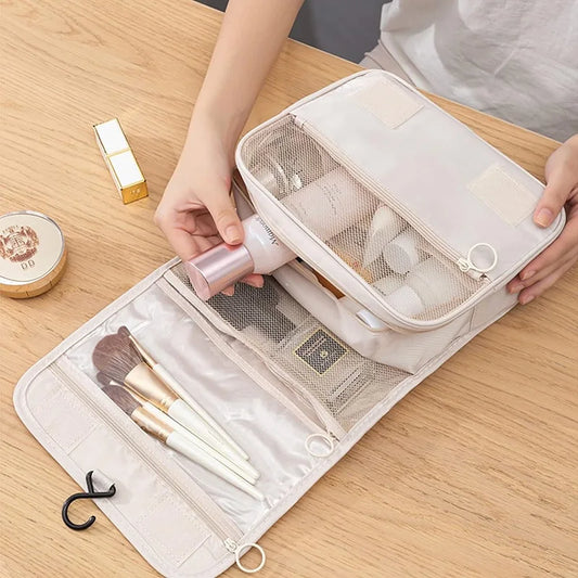 Beige waterproof travel toiletry bag with multiple mesh compartments, a hook, and a person organizing items.