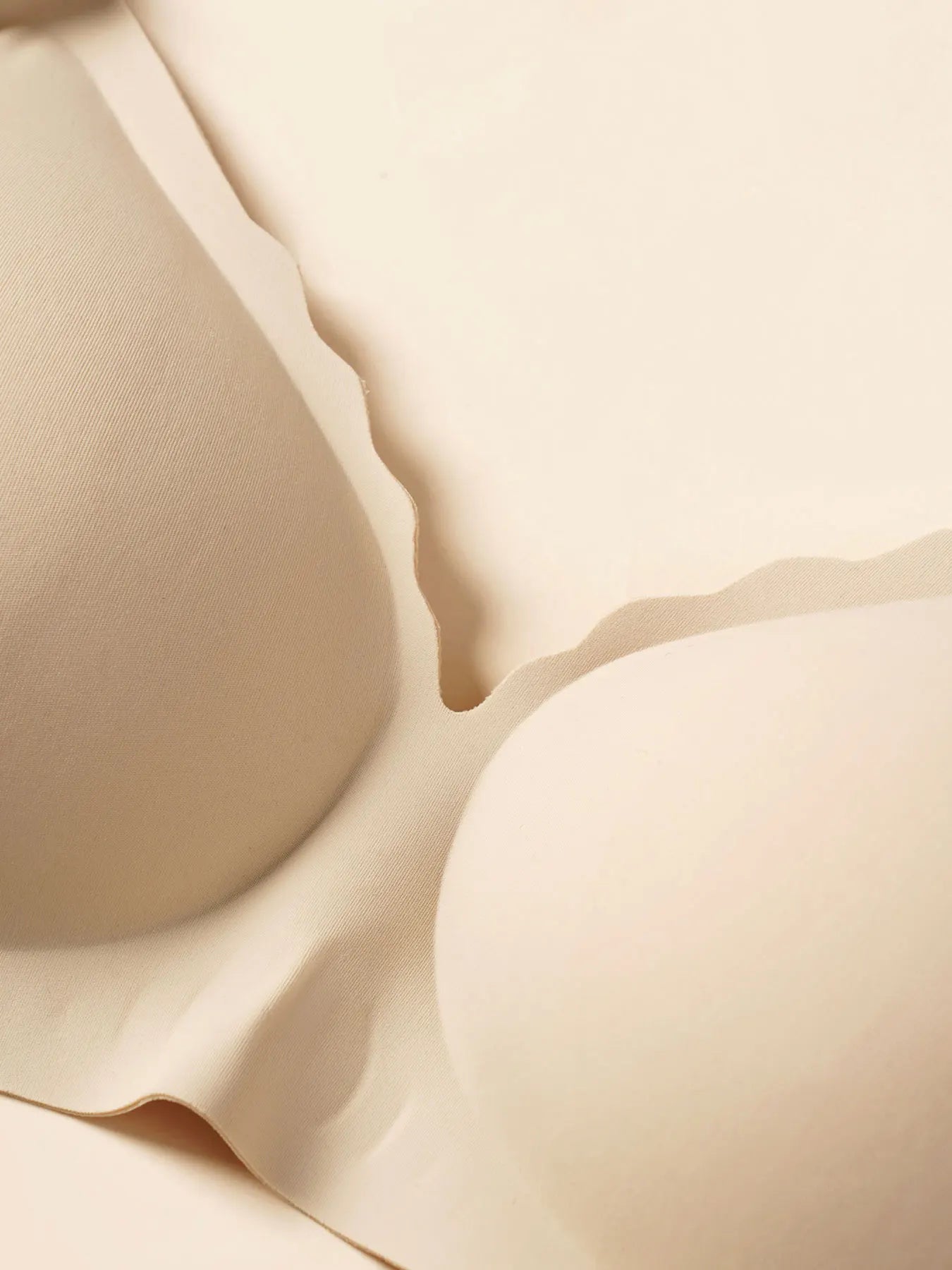 Close-up of a seamless, wire-free beige V-neck nursing bra with soft, flexible fabric.